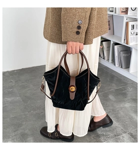 Detalle del bolso de nailon negro con correa de cuero marrón y hebilla de ámbar