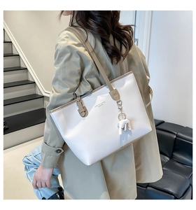 Detail of white tote bag with contrast piping and a cute elephant leather charm accessory