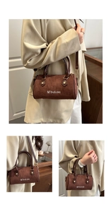 Detail of brown suede Boston bag showing the cylindrical structure and leather handles