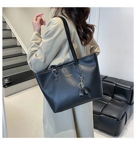 Detail of a black large-capacity tote bag with gold chain and elephant leather charm