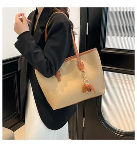 Detail of contrast stitching tote bag with small elephant charm worn on shoulder