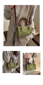 Detail of green suede Boston bag featuring brown leather straps and gold-tone hardware