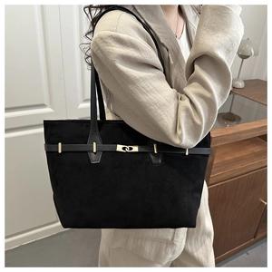 Detail of black suede tote bag with gold metal buckles and rivets on matte texture
