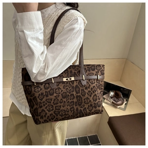 Detail einer Shopper-Tasche mit Leopardenmuster, braunen Lederriemen und Goldschnalle