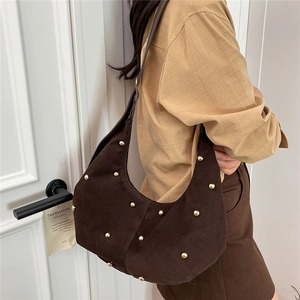 Retro brown suede crescent tote bag with gold studs shown as a crossbody shoulder bag