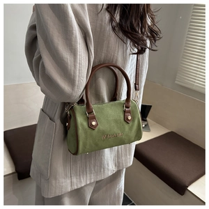 Detail of green Boston barrel bag featuring brown leather handles and M'DeLnu embroidery
