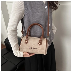 Macro shot of beige suede Boston bag with brown leather handles and brand embroidery