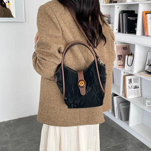 Bolso tipo cubo plisado negro con asas de cuero marrón y hebilla de ámbar única
