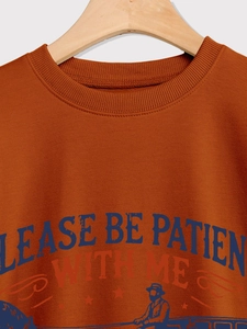 Detail of burnt orange sweatshirt neckline and PLEASE BE PATIENT WITH ME printed graphics