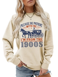 Detailed view of vintage horse carriage print and 'PLEASE BE PATIENT' slogan on cream sweatshirt