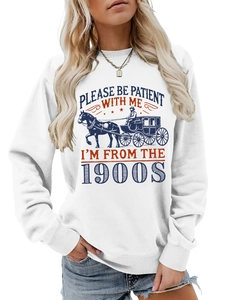 Close-up of 'PLEASE BE PATIENT' slogan and vintage carriage print on white sweatshirt