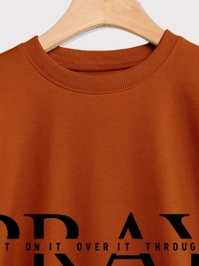 Detailed view of ribbed crew neck and black vintage text print on burnt orange sweatshirt