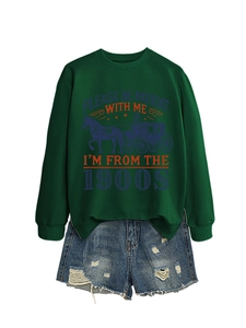 Close-up of a dark green sweatshirt with a vintage carriage print and distressed denim shorts