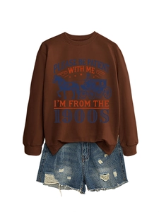 Detail of brown sweatshirt with 'Please be Patient' print and distressed denim shorts