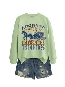 Flat lay of a mint green sweatshirt with 1900s slogan and distressed denim shorts