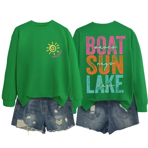Flat lay of green sweatshirt with Lake Days print and blue denim shorts with frayed edges