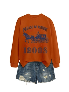 Flat lay of orange sweatshirt with vintage carriage print and distressed denim shorts