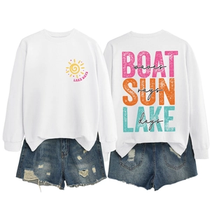 Flat lay of white long sleeve sweatshirt with Lake Days sun print and distressed denim shorts