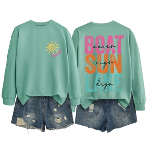Flat lay of mint green sweatshirt with 'LAKE DAYS' print and distressed denim shorts