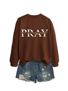 Flat lay of brown PRAY crewneck sweatshirt paired with blue distressed denim shorts