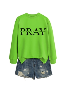 Neon green sweatshirt with Pray slogan paired with distressed blue denim shorts