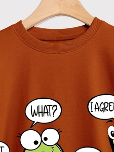 Detail of caramel sweatshirt featuring a cute cartoon frog graphic and ribbed crew neck