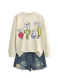 Flat lay of a beige sweatshirt with cartoon graphics paired with distressed denim shorts