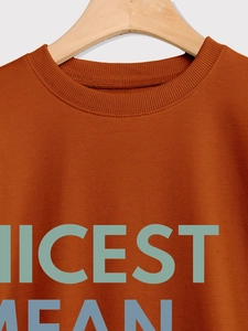 Detail of caramel orange sweatshirt featuring ribbed crew neck and Nicest Mean Teacher print