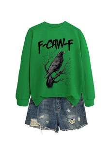 Dettaglio felpa verde oversize con grafica a corvo e pantaloncini di jeans sfrangiati