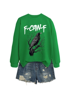 Dettaglio flat lay di felpa verde con grafica aquila e pantaloncini in denim strappati
