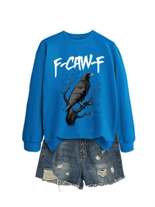 Dettaglio della felpa blu con stampa a corvo e pantaloncini in denim sfrangiati da donna