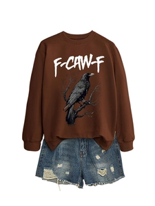 Dettaglio della stampa grafica con aquila su felpa marrone oversize e pantaloncini denim