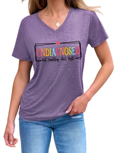 Gros plan détaillé de l'imprimé arc-en-ciel et du texte sur un t-shirt violet à col en V
