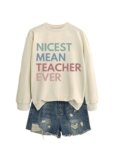 Detail of Nicest Mean Teacher Ever beige sweatshirt paired with ripped denim shorts