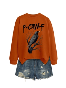 Flat lay di felpa arancione girocollo con stampa corvo e pantaloncini di jeans