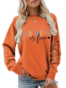 Détail de l'imprimé Kindness is Free et du motif cœur sur la manche du sweat-shirt orange