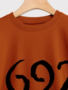 Detail of terracotta sweatshirt with ribbed crew neck and bold black graphic print