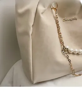 Dettaglio della borsa tote in ecopelle crema con logo Sunnycity in metallo e perle