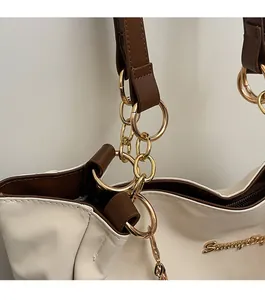 Dettaglio dell'elegante catena dorata multistrato sulla borsa shopping color crema