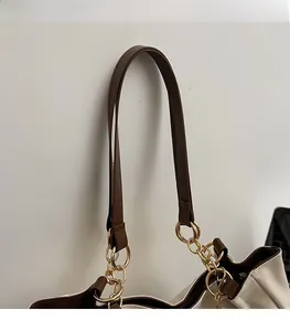 Dettaglio della tracolla larga in pelle marrone con catena in metallo dorato su borsa