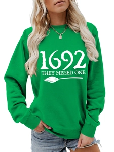 Close-up of 1692 They Missed One slogan and broom print on green crewneck sweatshirt
