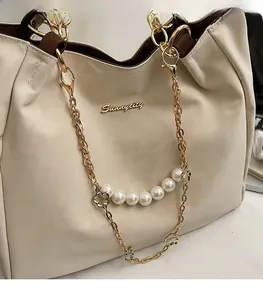 Dettaglio della borsa beige con logo Sunnycity, catena dorata e ciondolo di perle