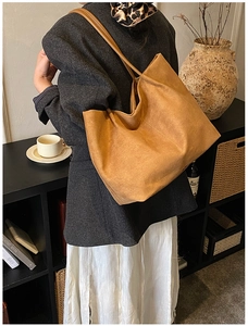 Dettaglio della borsa tote in pelle scamosciata caramello con tracolla sottile su modella