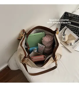 Dettaglio degli interni capienti della borsa crema con tablet, ombrello e portafoglio