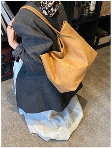 Detail view of khaki matte suede tote bag shown in a professional lifestyle setting