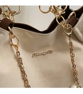 Detail of texture cream tote with golden Sunnicity logo and thick metal chain link