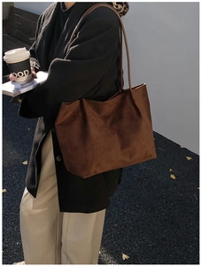 Detail of a large dark brown suede tote bag with minimalist slim straps for daily use