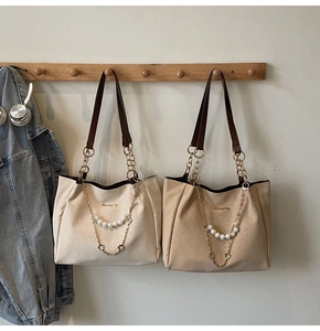 Detailed view of tote bags with pearl metal chains and logo on smooth fabric