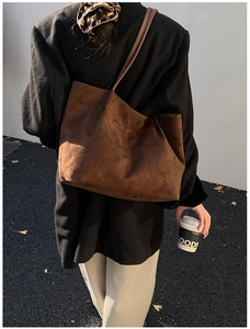 Minimalist large brown suede tote bag shown on shoulder in stylish urban outdoor setting
