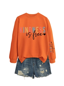 Détail du slogan Kindness is free sur sweat orange avec short en jean délavé